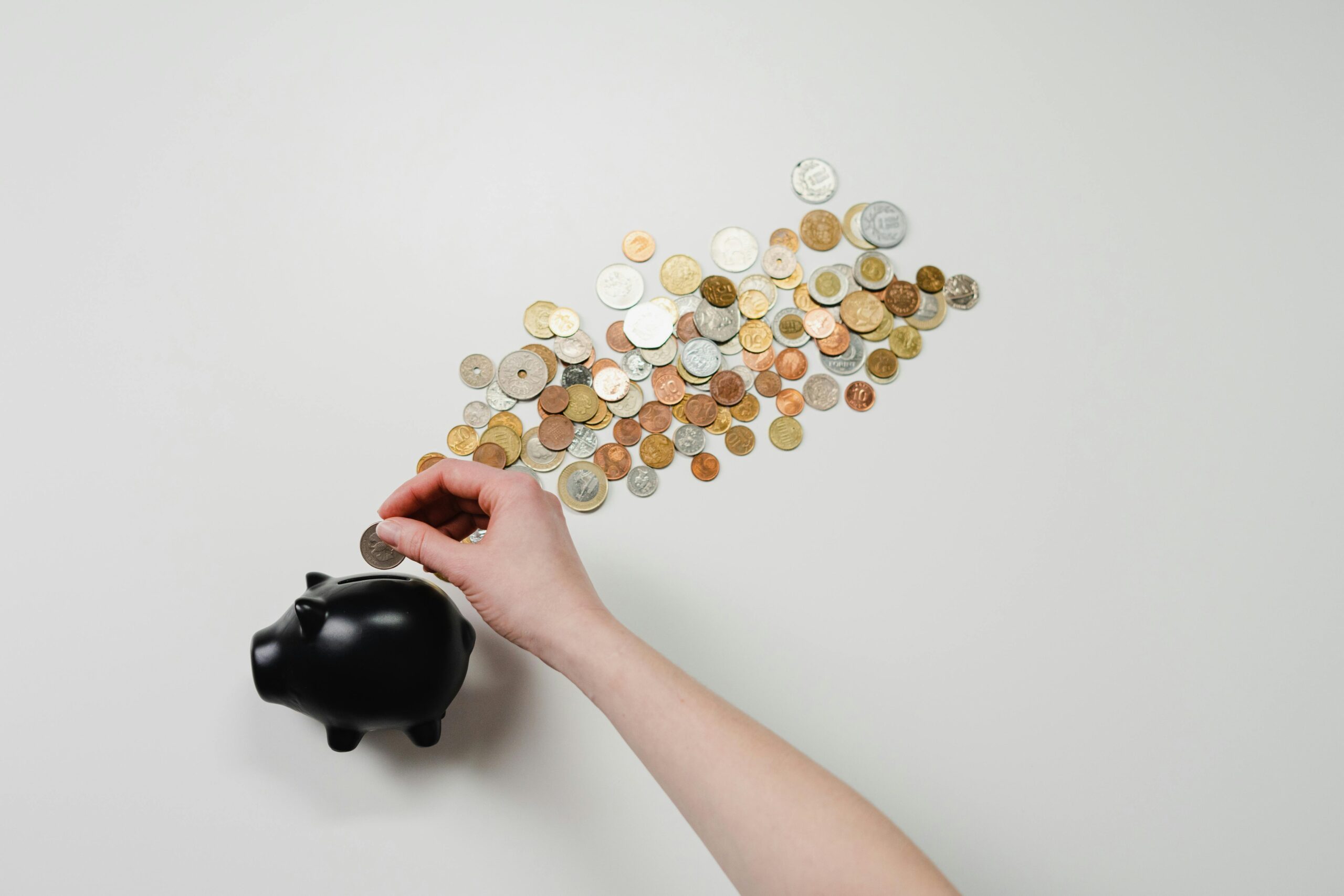 Hand pouring coins change out of a piggy bank