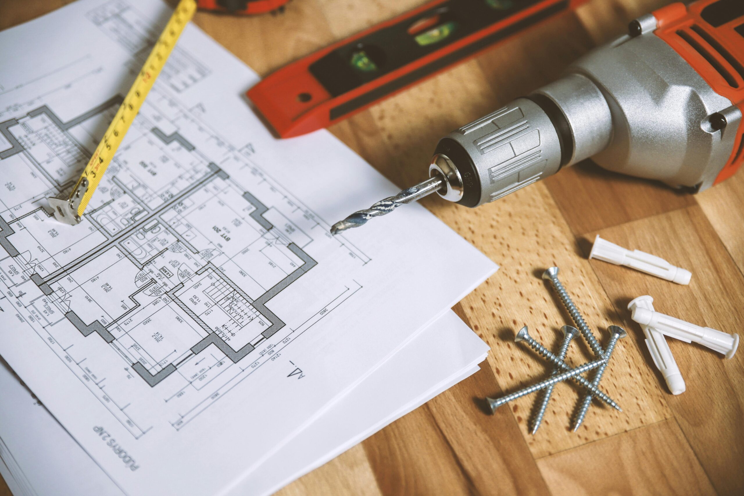 Construction tools over a table and house blueprint.