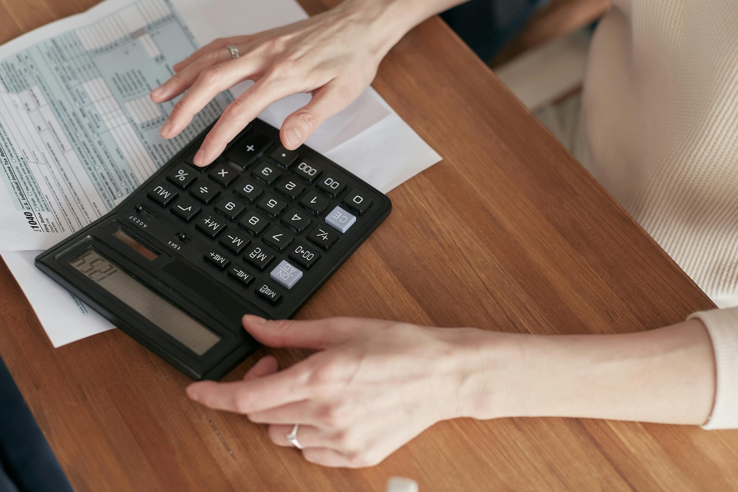 Closeup of hands using a calculator with financial documents on table