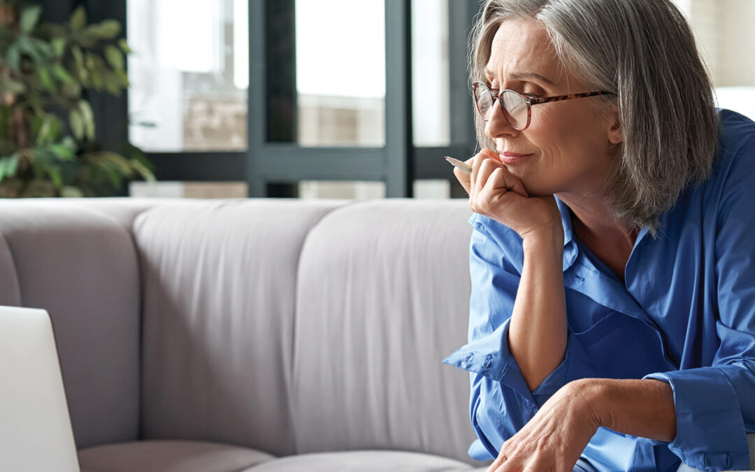 Person looking in the distance while financial papers are spread out on the coffee table.