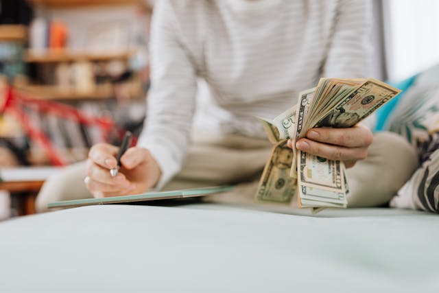 Person counting money at table and is writing notes